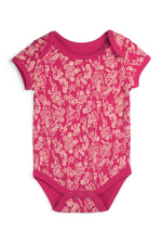 A short-sleeve baby bodysuit in vibrant magenta pink, featuring an all-over cream floral and botanical pattern, laid flat against a white background. 