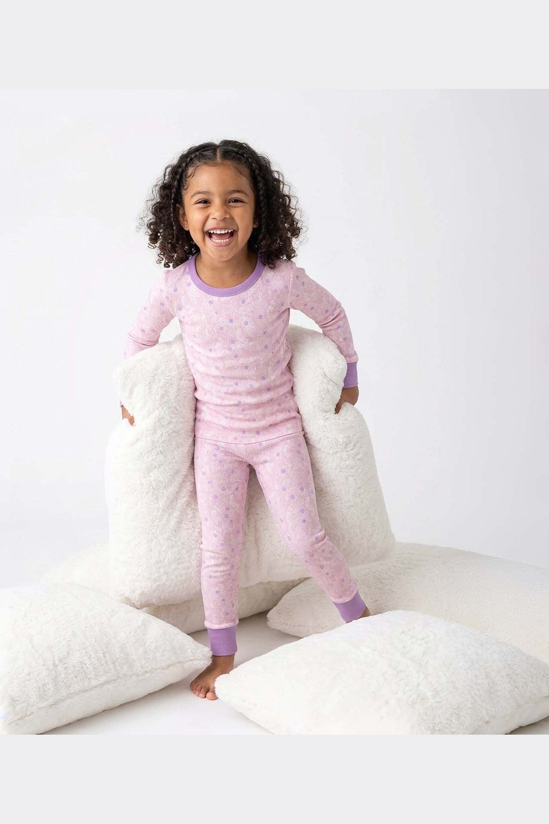 Child wearing pink pajamas with a white pillow background