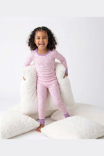 Child wearing pink pajamas with a white pillow background