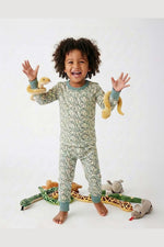 Child wearing a green snake pajamas with toys on a white background 
