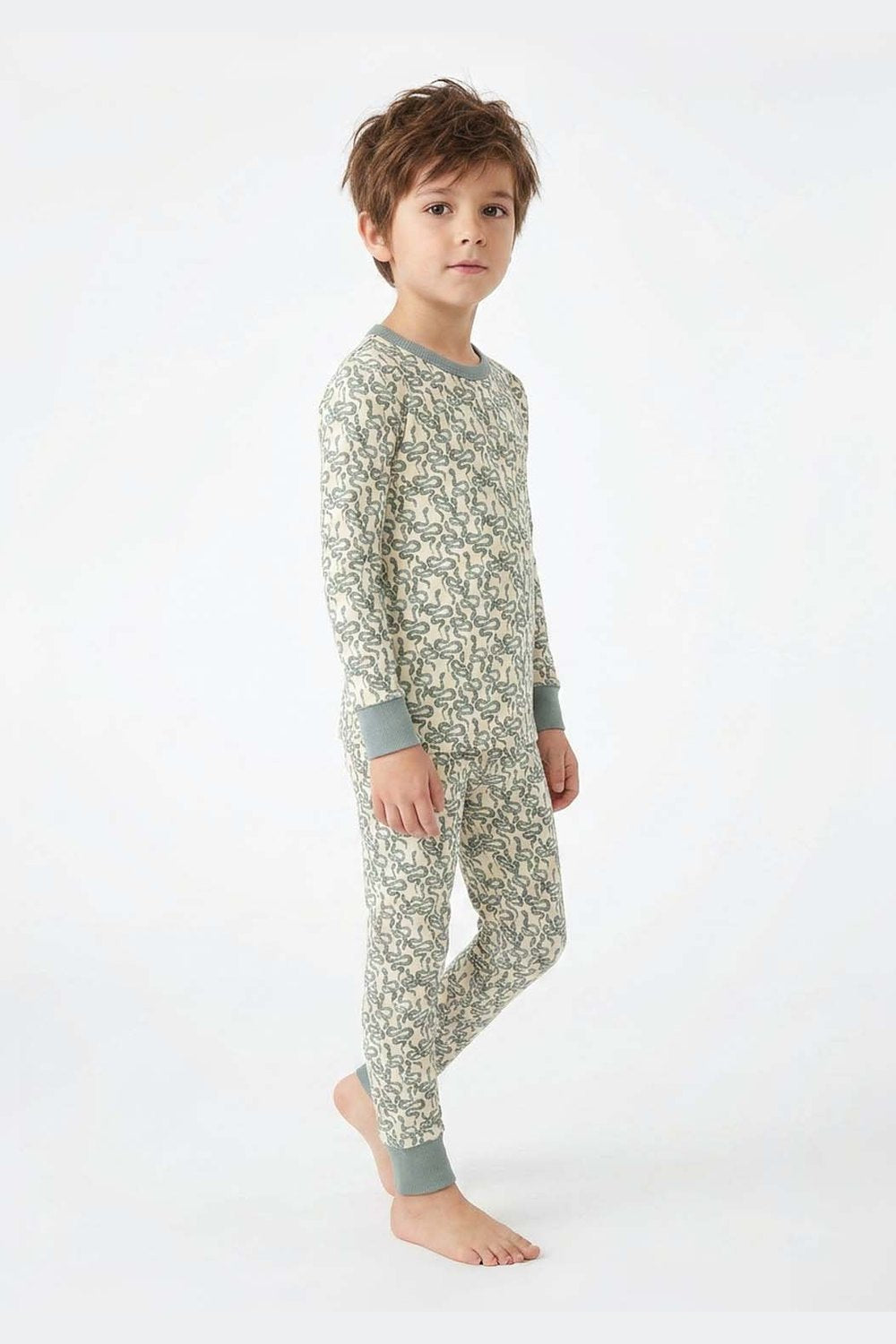 Child wearing a green snake patterned pajama set on a white background 