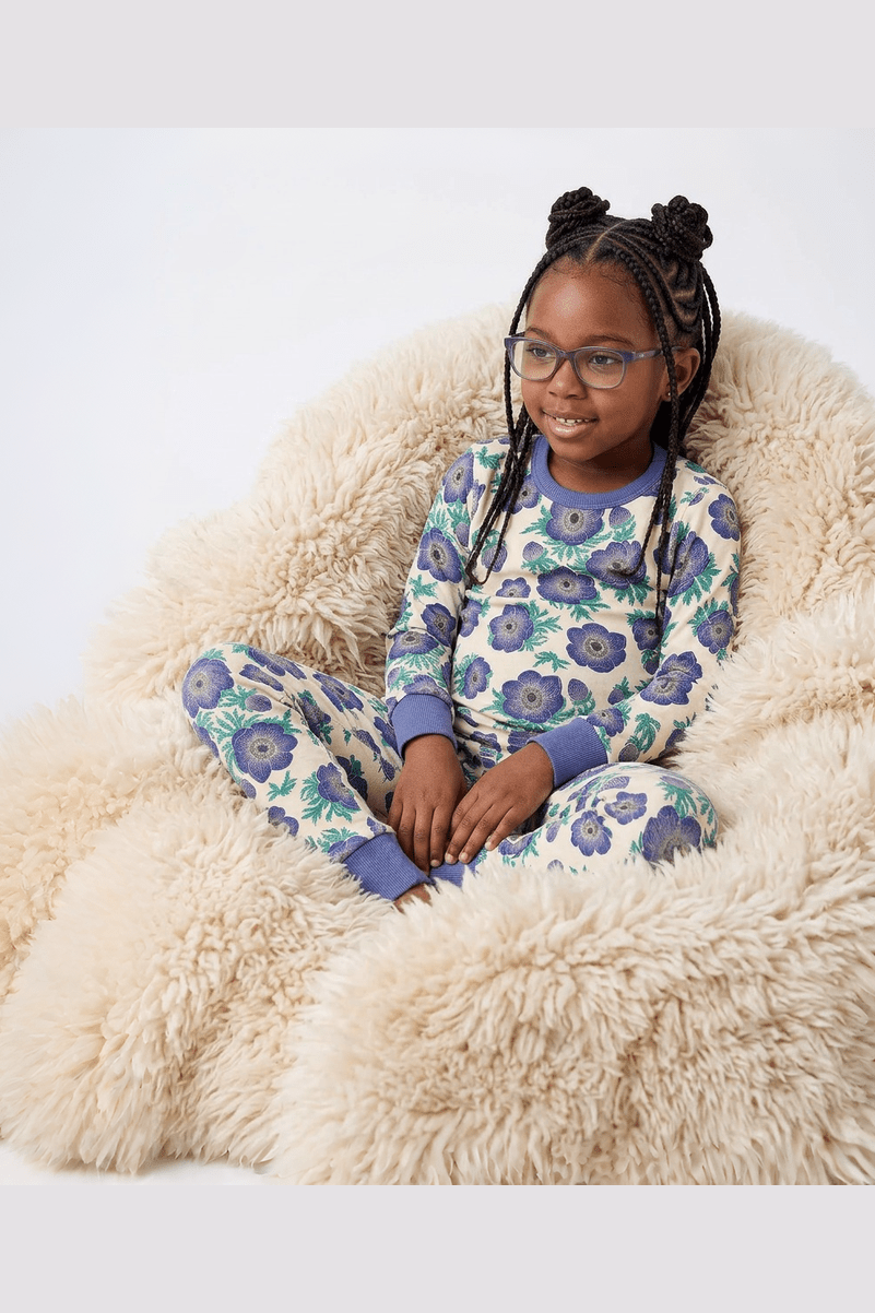 Young girl wearing a floral pajama set sitting on a fluffy chair.