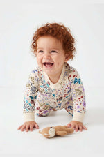 Baby in a floral onesie with a toy on a white background 