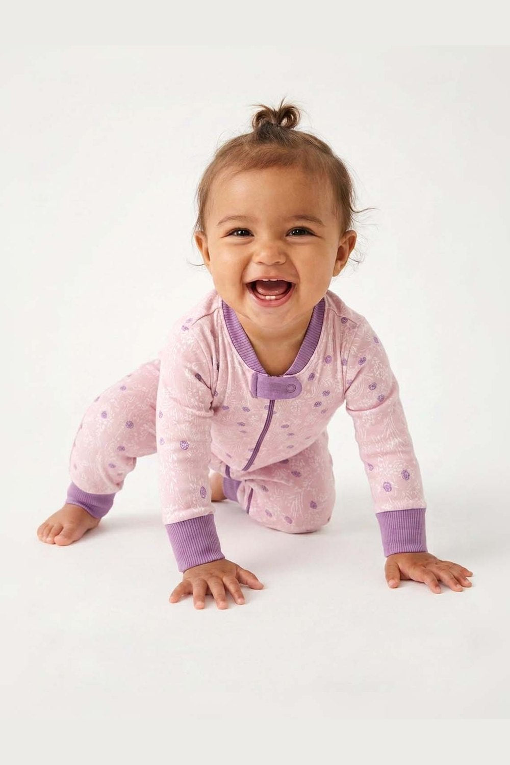 Baby in a pink and purple outfit with a white background 