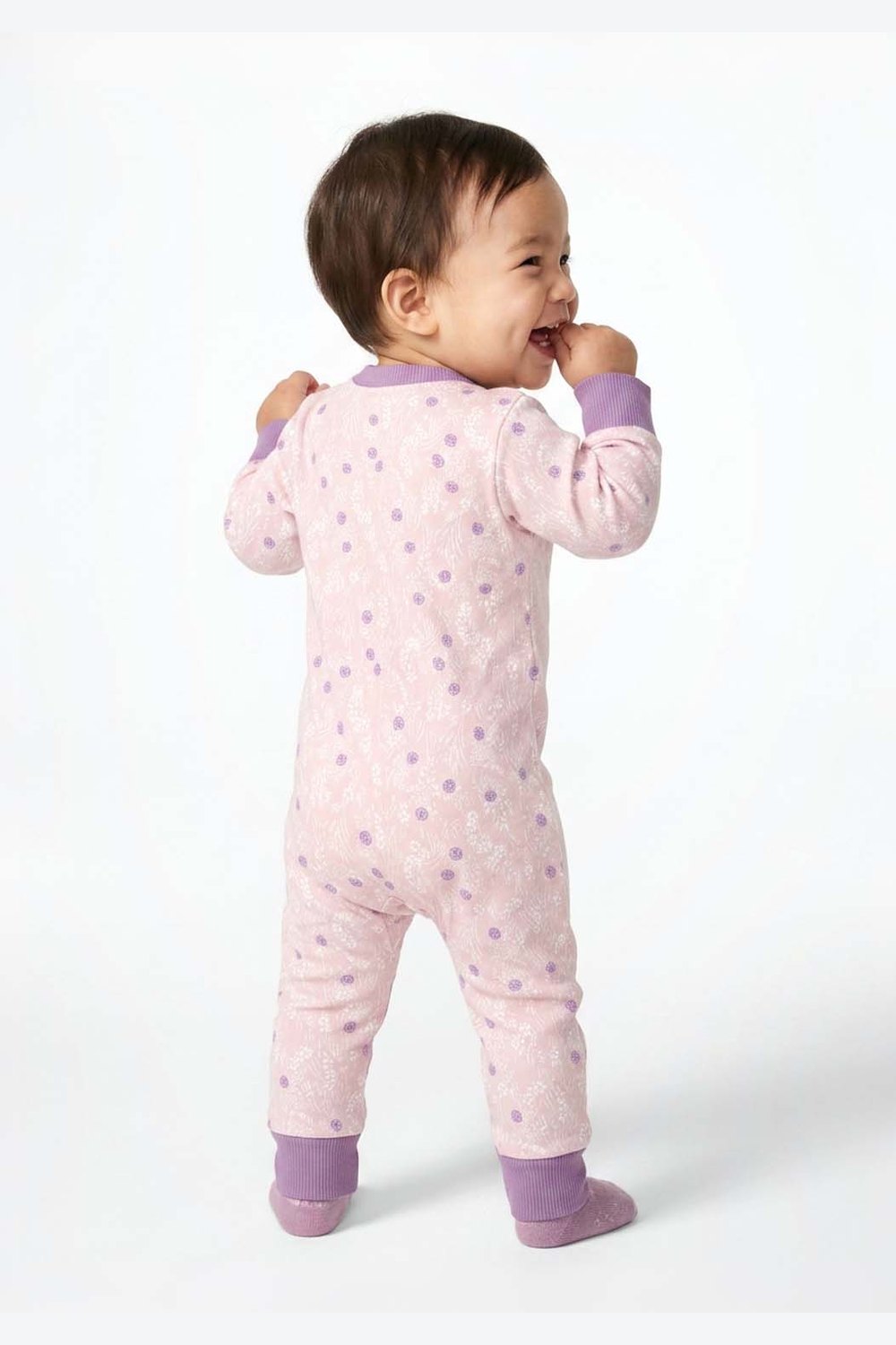 Baby wearing a pink onesie with purple accents on a white background 