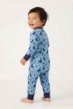 Baby standing wearing a blue pajama with animal pattern on a white  background 