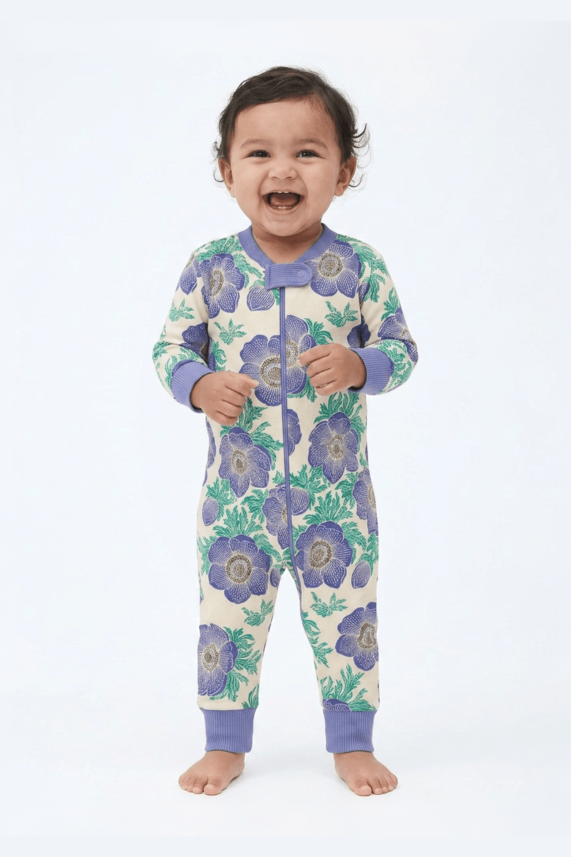 Baby wearing a floral patterned onesie with purple flowers on a white background #purple-poppies