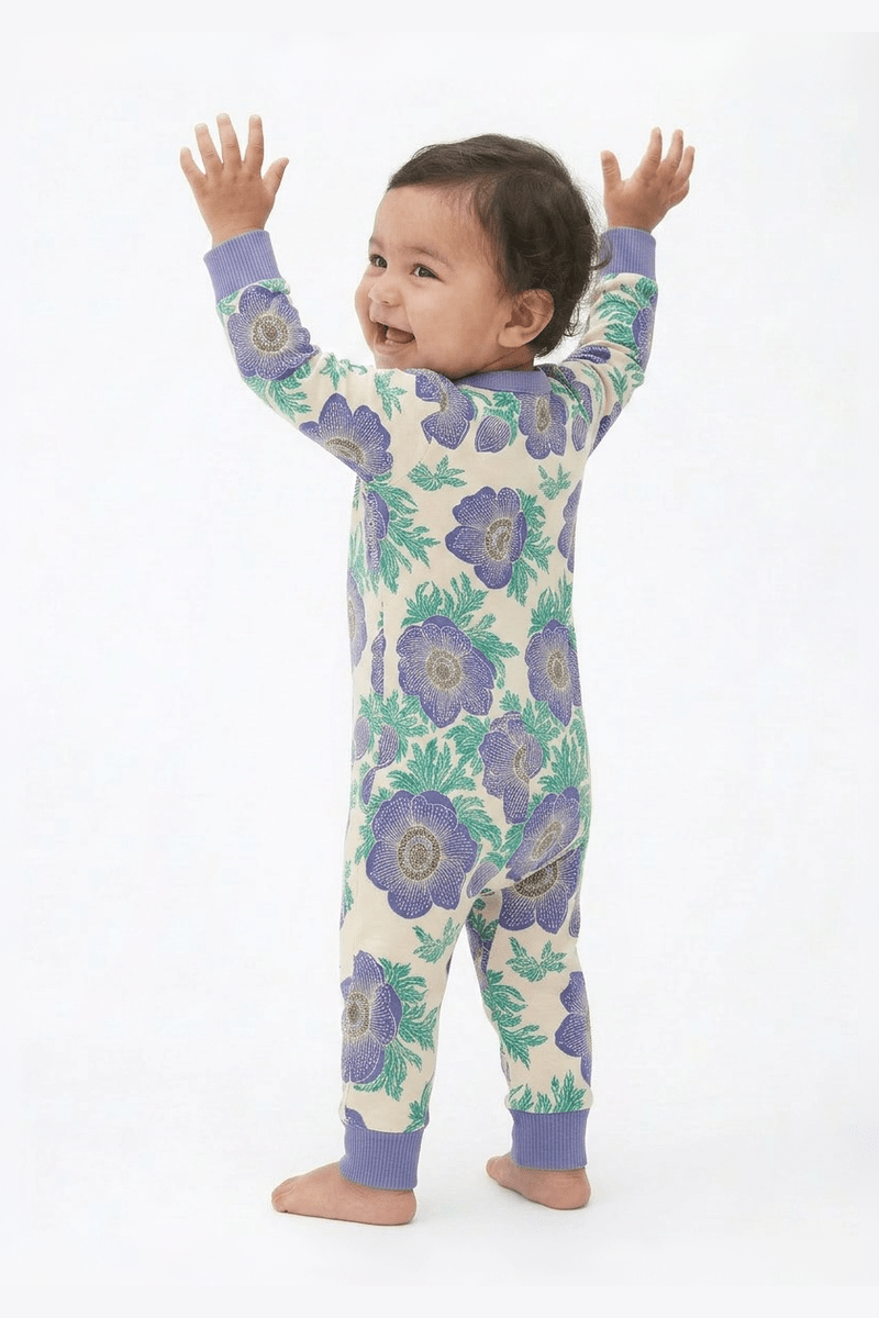 Baby wearing a floral onesie with arms raised on a white background 