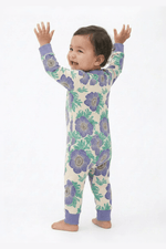 Baby wearing a floral onesie with arms raised on a white background 
