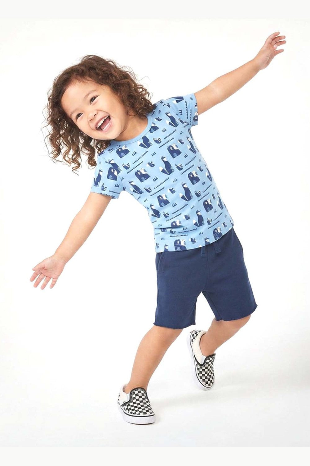 Child wearing a blue patterned shirt and navy shorts on a white background 