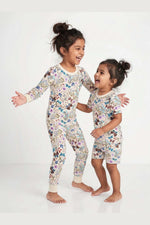 Two children wearing matching floral pajamas on a white background 