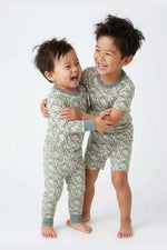 Two children wearing matching green snake pajamas on a white background 