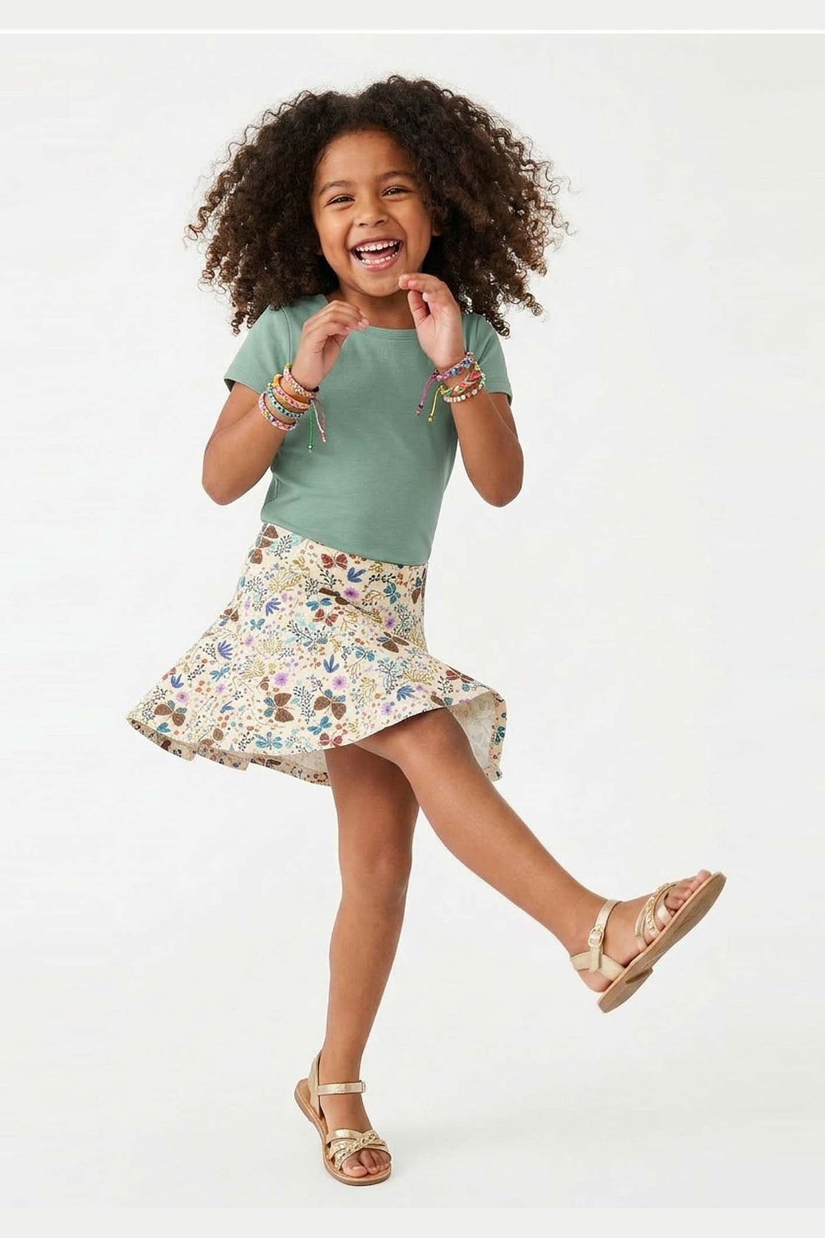 Young girl in a green shirt and floral skirt on a white background