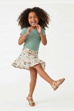 Young girl in a green shirt and floral skirt on a white background