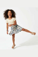 Child wearing a floral skirt and ivory top on a white background