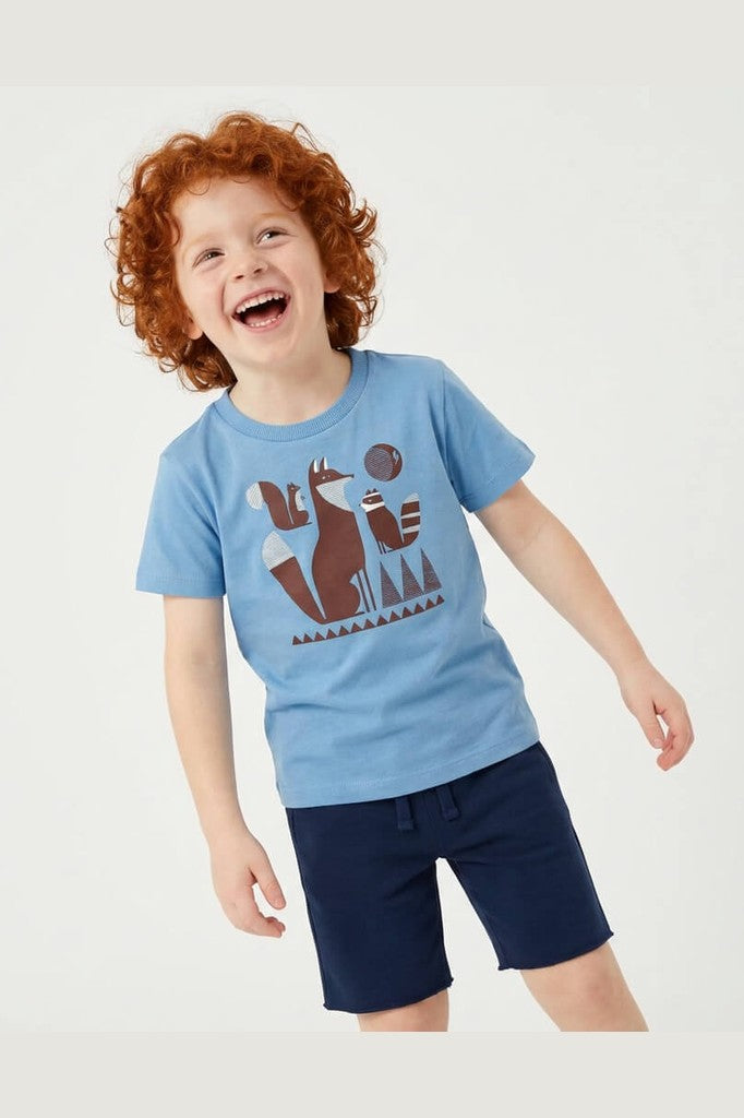 Young boy with red hair wearing a Mightly 100% organic cotton graphic tee with a colorful fox print and navy shorts. 