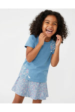 Young girl wearing a Mightly 100% organic cotton graphic tee with a pink and white print featuring flowers and bunnies and a matching skirt. 