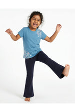 Young girl wearing a Mightly 100% organic cotton graphic tee with a pink and white print featuring flowers and bunnies and navy blue pants. 
