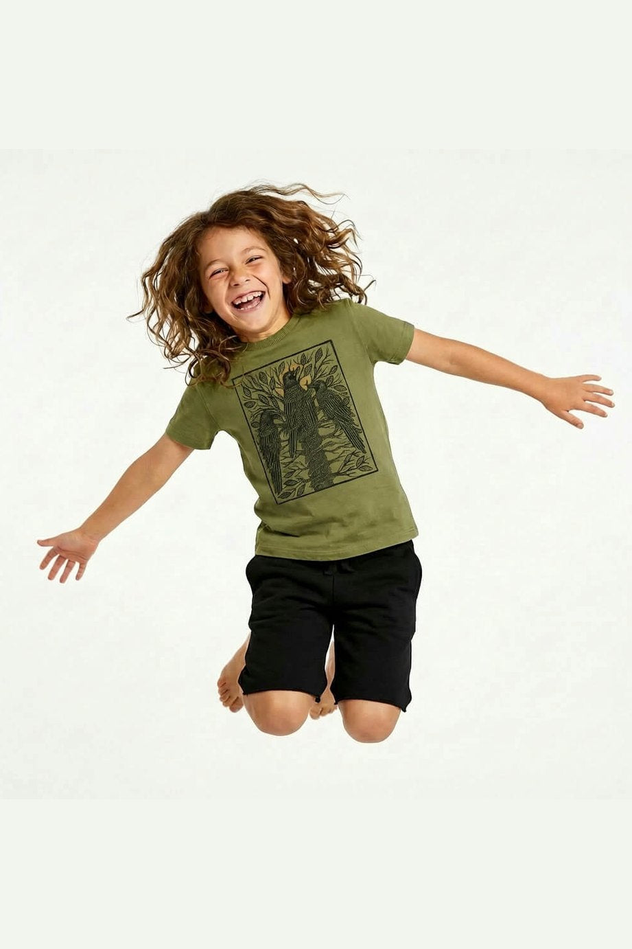 Jumping child wearing a Mightly 100% organic cotton graphic tee with a black crow print and black shorts 