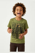 Young child wearing a Mightly 100% organic cotton graphic tee with a black crow print and brown pants. 