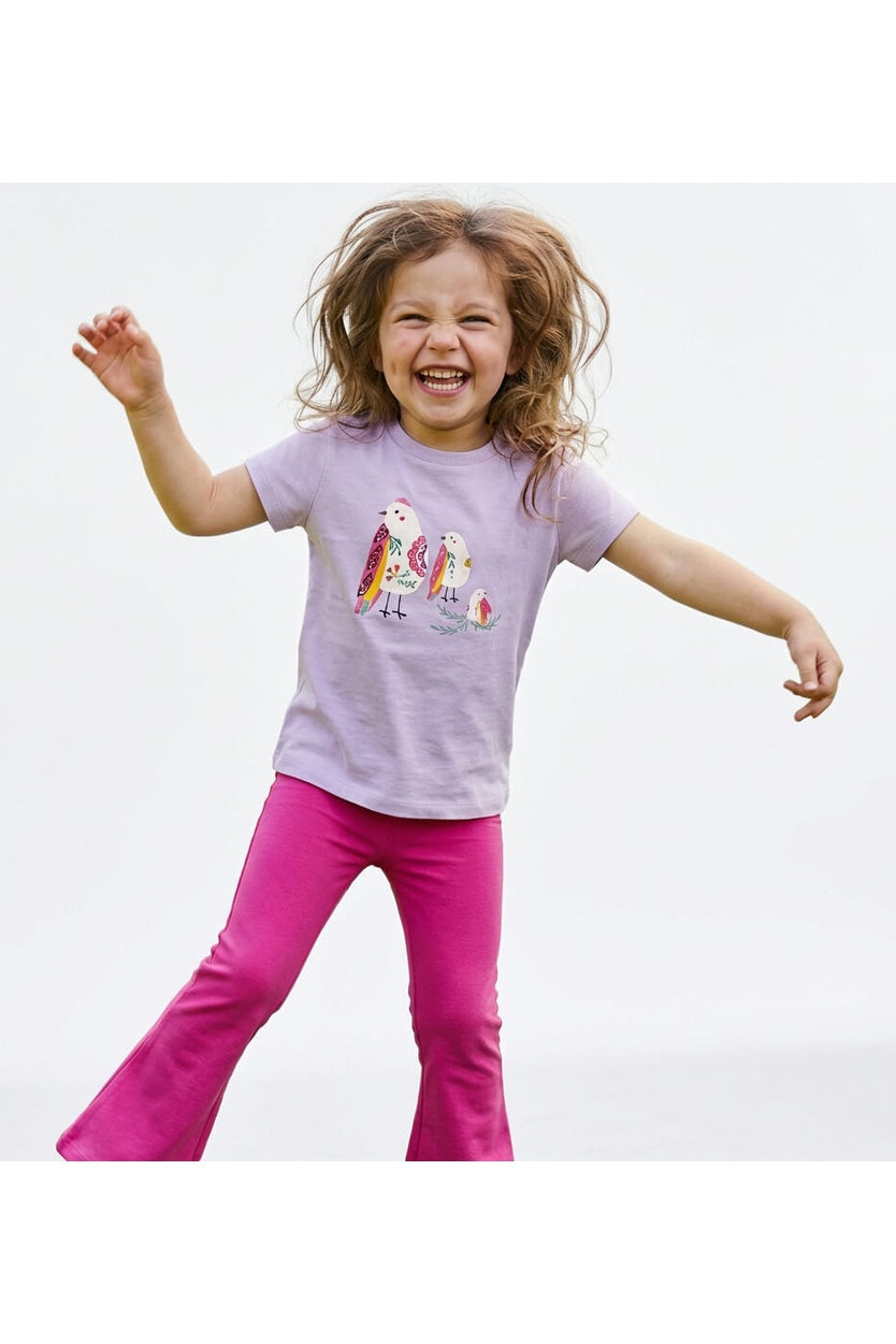 Young girl wearing a Mightly 100% organic cotton graphic tee with a colorful bird print and bright pink pants. 