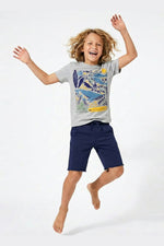 Child wearing a gray t-shirt with a colorful design and navy shorts, jumping on a white background 