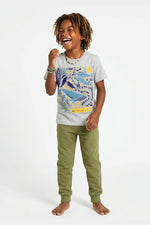 Child wearing a gray t-shirt with a colorful whale design and green pants on a white background 
