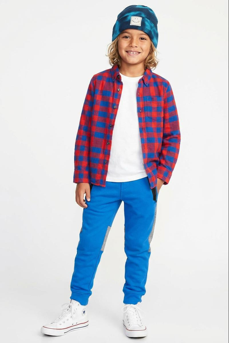 Child wearing a red and blue plaid shirt, white sneakers, and blue pants on a white background