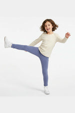 Child wearing a white long-sleeve shirt and purple leggings on a white background
