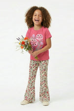 Child wearing a pink shirt with a flower design and floral pants, holding flowers on a white background
