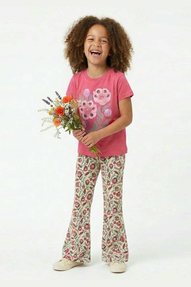 Child wearing a pink shirt with a flower design and floral pants, holding flowers on a white background