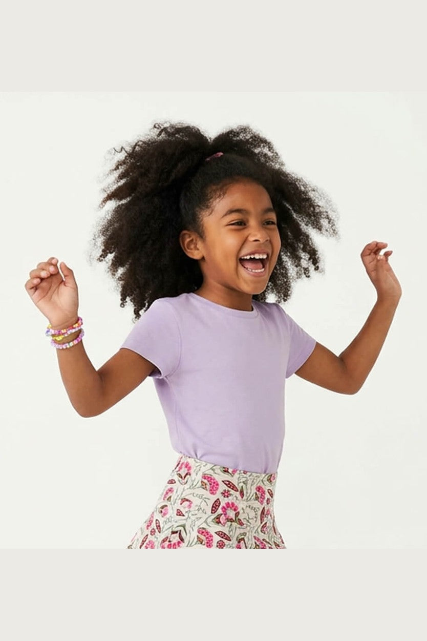 Child wearing a purple shirt and floral skirt on a white background
