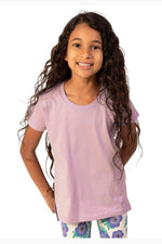 Young girl wearing a light purple t-shirt and patterned leggings on a white background 