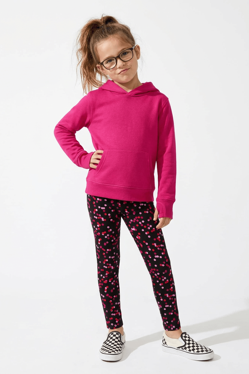 Girl wearing a pink hoodie and patterned leggings on a white background