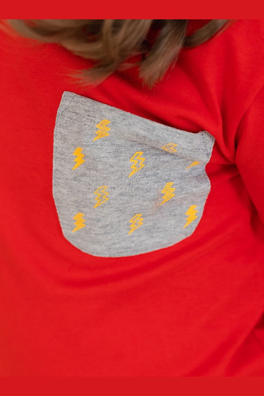 close up view of a gray lightning bolt print pocket on a red shirt